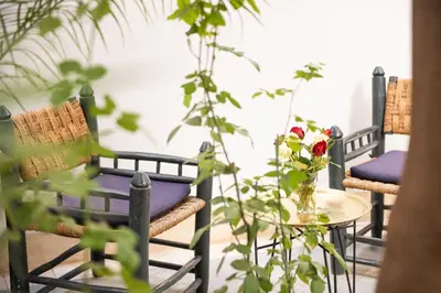 a patio with three chairs and a table with flowers at Riyad El Cadi in Marrakech