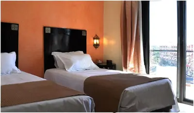 two beds in a hotel room with a window at Mont Gueliz in Marrakech