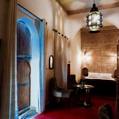a room with a bed and a table and a window at Riad Les Trois Palmiers El Bacha in Marrakech