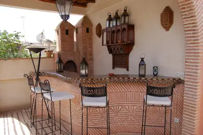 an outdoor bar with stools and a table at Riad Les Trois Palmiers El Bacha in Marrakech