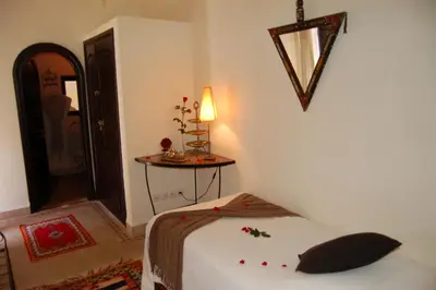a bedroom with a bed and a table with a lamp at Riad Les Trois Palmiers El Bacha in Marrakech