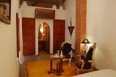 a living room with chairs and a table and a door at Riad Les Trois Palmiers El Bacha in Marrakech