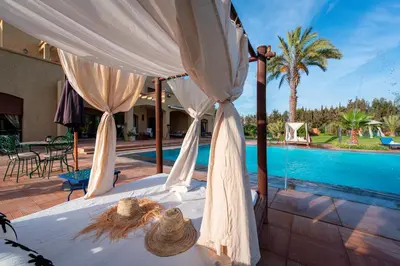 a bed with a canopy in front of a pool at Palais les sources de l'atlas, Padel & spa in Marrakech