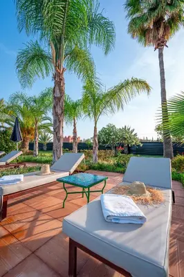 a row of beds on a patio with palm trees at Palais les sources de l'atlas, Padel & spa in Marrakech