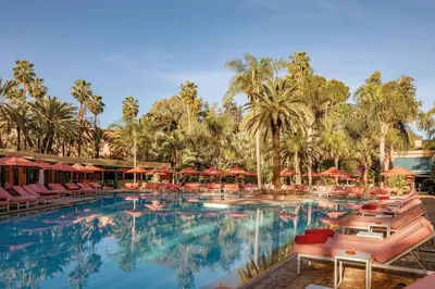 a pool at a resort with chairs and palm trees at Es Saadi Marrakech Resort - Hotel in Marrakech
