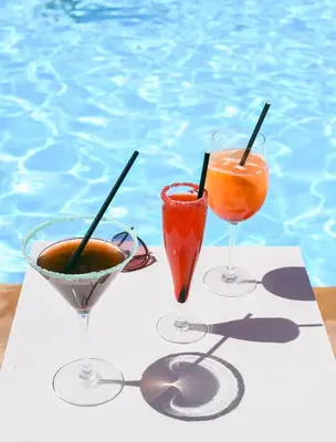 three drinks on a table next to a swimming pool at Es Saadi Marrakech Resort - Hotel in Marrakech
