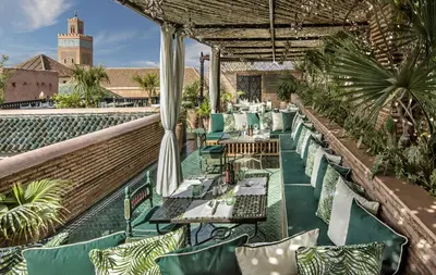 a restaurant with green chairs and tables on a roof at La Sultana Marrakech in Marrakech