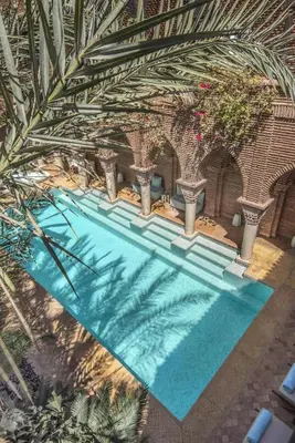 an overhead view of a swimming pool with palm trees at La Sultana Marrakech in Marrakech