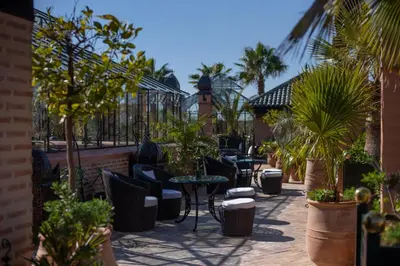 a patio with tables and chairs and palm trees at La Sultana Marrakech in Marrakech
