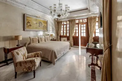 a bedroom with a bed and a chair and a chandelier at La Sultana Marrakech in Marrakech