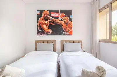 two beds in a room with a painting of a boxing match at Résidence Golfique PJ, jardin, piscine in Marrakech