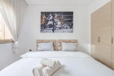 a bedroom with a large bed with white sheets at Résidence Golfique PJ, jardin, piscine in Marrakech