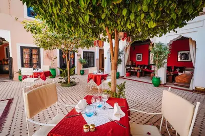 a restaurant with a red table and chairs and trees at Les Borjs De La Kasbah in Marrakech