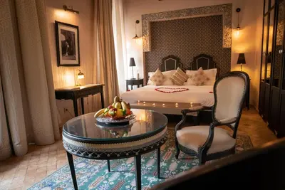 a hotel room with a bed and a table and chairs at Demeures d'Orient Riad & Spa in Marrakech