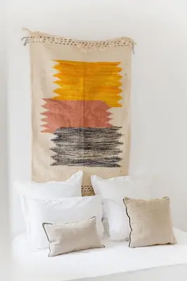 a tapestry hanging above a bed with pillows at Riad 27 & SPA entièrement privatisé in Marrakech