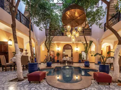 a lobby with a pool and trees and a chandelier at Riad Dar El Médina - Heated Swimming pool, jacuzzi & Spa in Marrakech
