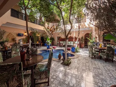 a restaurant with a pool with tables and chairs at Riad Dar El Médina - Heated Swimming pool, jacuzzi & Spa in Marrakech