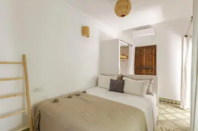 a white bedroom with a bed and a ladder at Riad Privé Dar Yaël in Marrakech