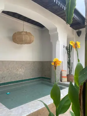 a swimming pool in a villa with yellow flowers at Riad Dar Balthazar in Marrakech