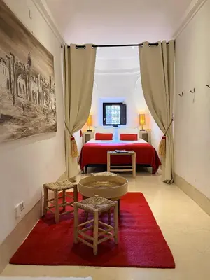 a bedroom with a red bed and a red rug at Riad Dar Balthazar in Marrakech