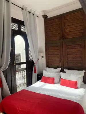 a bedroom with a bed with two red pillows at Riad Dar Balthazar in Marrakech