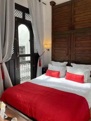 a bedroom with a large bed with red pillows at Riad Dar Balthazar in Marrakech