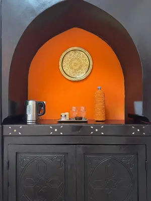 a black cabinet with a plate on an orange wall at Riad Dar Balthazar in Marrakech