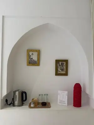 a shelf with a coffee pot and two pictures on a wall at Riad Dar Balthazar in Marrakech