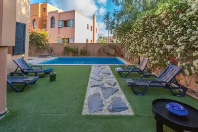 a yard with chairs and a swimming pool with a table at Villa Dahlia in Marrakech