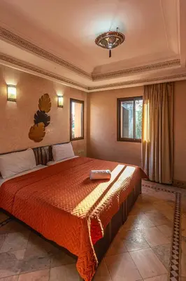 a bedroom with a large bed with a red bedspread at Villa Dahlia in Marrakech