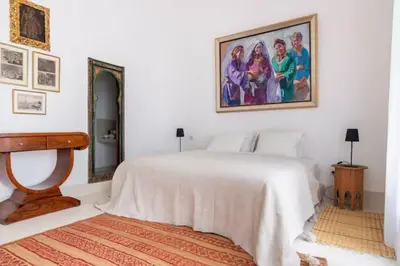 a white bedroom with a bed and a painting on the wall at DAR SAFIRA in Marrakech
