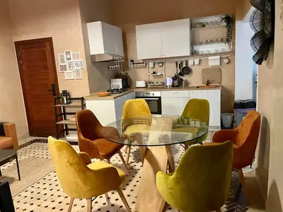 a kitchen with a glass table and yellow chairs at Au Riad des Deux Patios - Marrakech in Marrakech