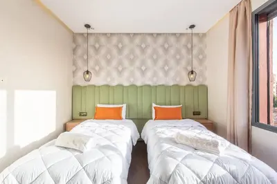 two beds with orange pillows in a room at Design, résidence standing, Salon modern, Terrasse in Marrakech