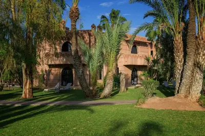 a building with palm trees in front of it at Villa Al Assala Palmeraie in Marrakech