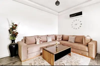 a living room with a couch and a clock on the wall at Magnifique appartement en plein centre ville in Marrakech