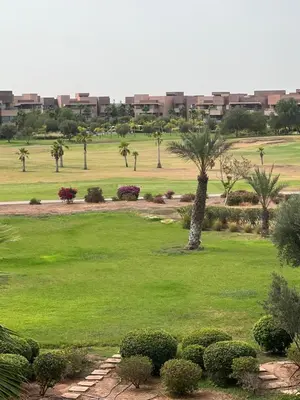 a park with palm trees and a field of grass at Marrakech Prestigia appartement vue piscine golf endroit calme in Marrakech