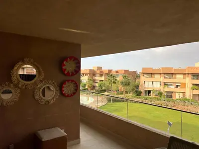 a room with a balcony with a view of a park at Super appartement familial avec piscine à Prestigia Marrakech in Marrakech