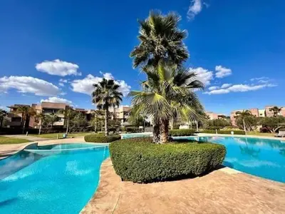 a palm tree sitting next to a swimming pool at Super appartement familial avec piscine à Prestigia Marrakech in Marrakech