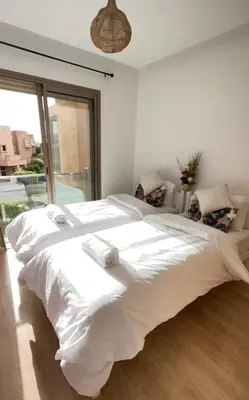 a large white bed in a room with a window at Super appartement familial avec piscine à Prestigia Marrakech in Marrakech