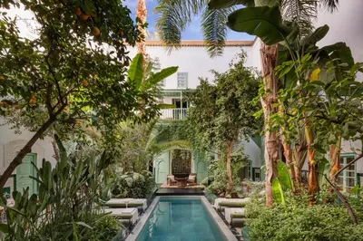a courtyard with a swimming pool in a building with trees at Riad Kitula in Marrakech