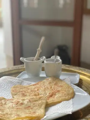 a plate with two pancakes and two cups on a table at Riad Rossi in Marrakech