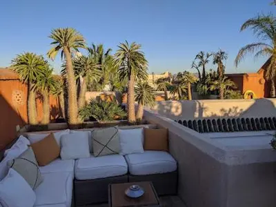 a patio with a couch and palm trees and a table at Riad Rossi in Marrakech