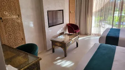 a hotel room with a bed and a table and a tv at Hôtel Jardins de lina et lea in Marrakech