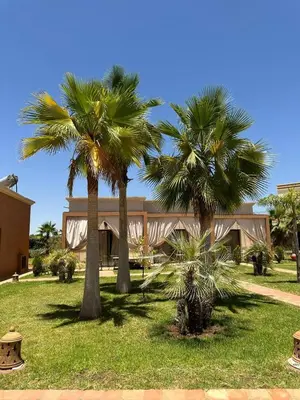 two palm trees in front of a building at Hôtel Jardins de lina et lea in Marrakech