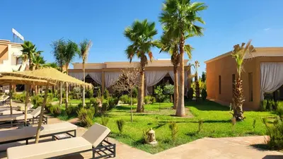 a resort with palm trees and a patio at Hôtel Jardins de lina et lea in Marrakech