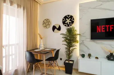 a dining room with a table and chairs and a tv at Appartement Chic Gueliz Plaza avec Vue in Marrakech