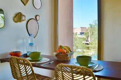 a table with two chairs and a bowl of fruit at Appartement, Prestigia Marrakech in Marrakech