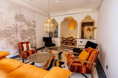 a living room with orange chairs and a table at Cosy Appartement 5min de Majorelle in Marrakech