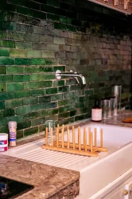 a bathroom sink with a green brick wall at Cosy Appartement 5min de Majorelle in Marrakech