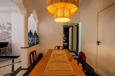 a dining room with a wooden table and a chandelier at Cosy Appartement 5min de Majorelle in Marrakech